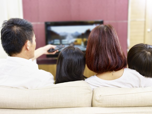 Family watching television from their living room couch.