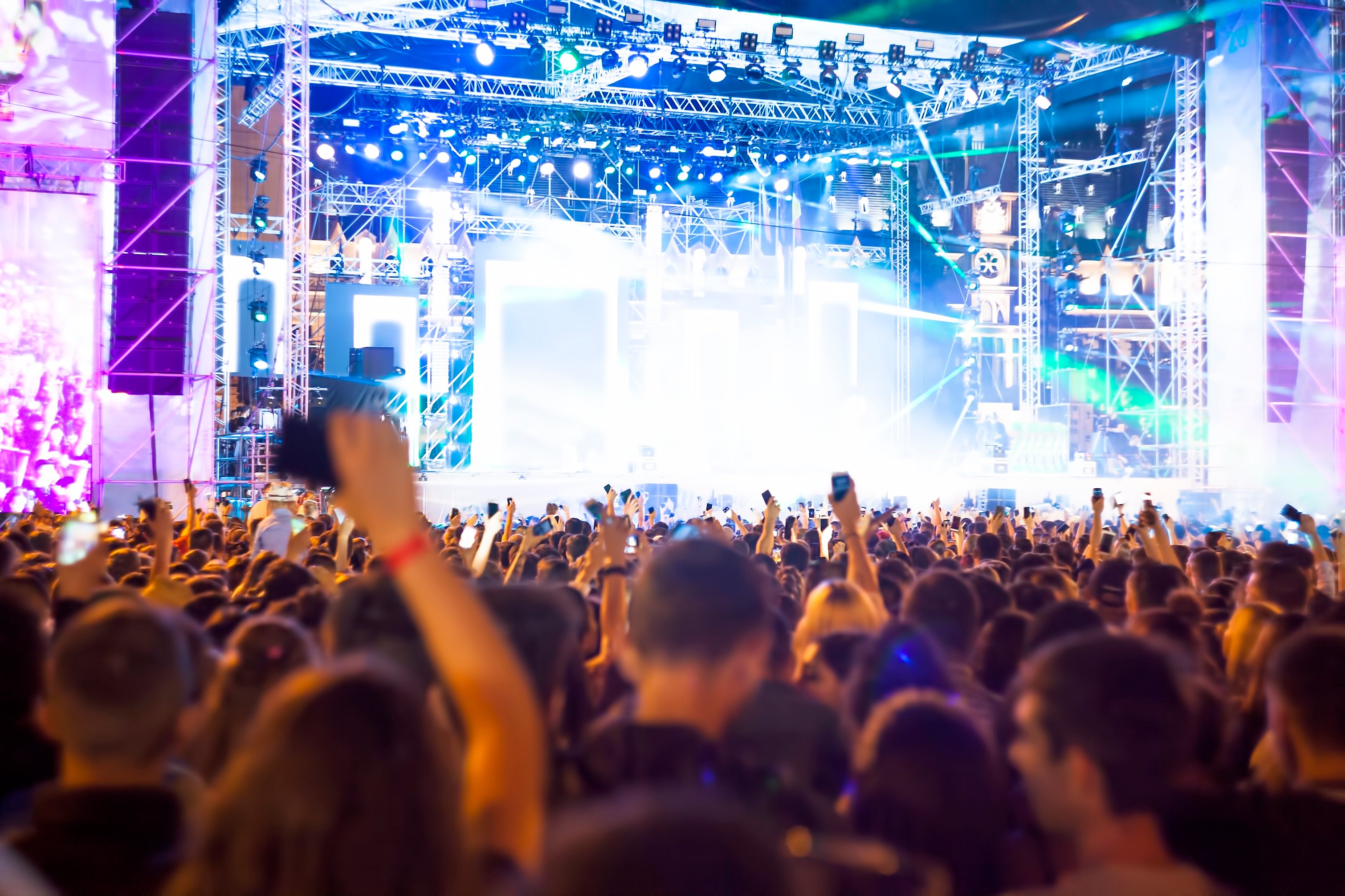 Crowd of people in front of a brightly lit concert stage.