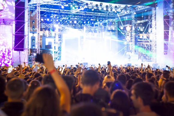 Crowd of people in front of a brightly lit concert stage.