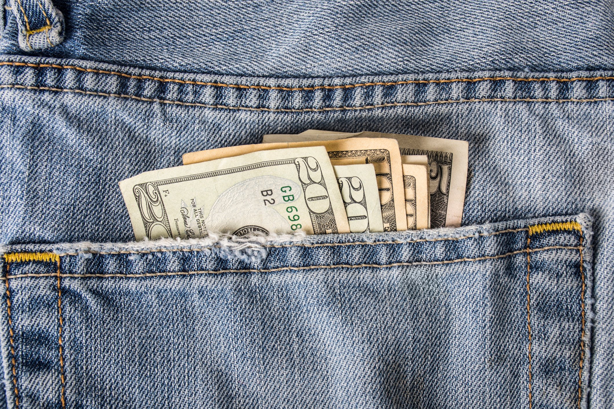 Cash sticking out from a jeans back pocket.