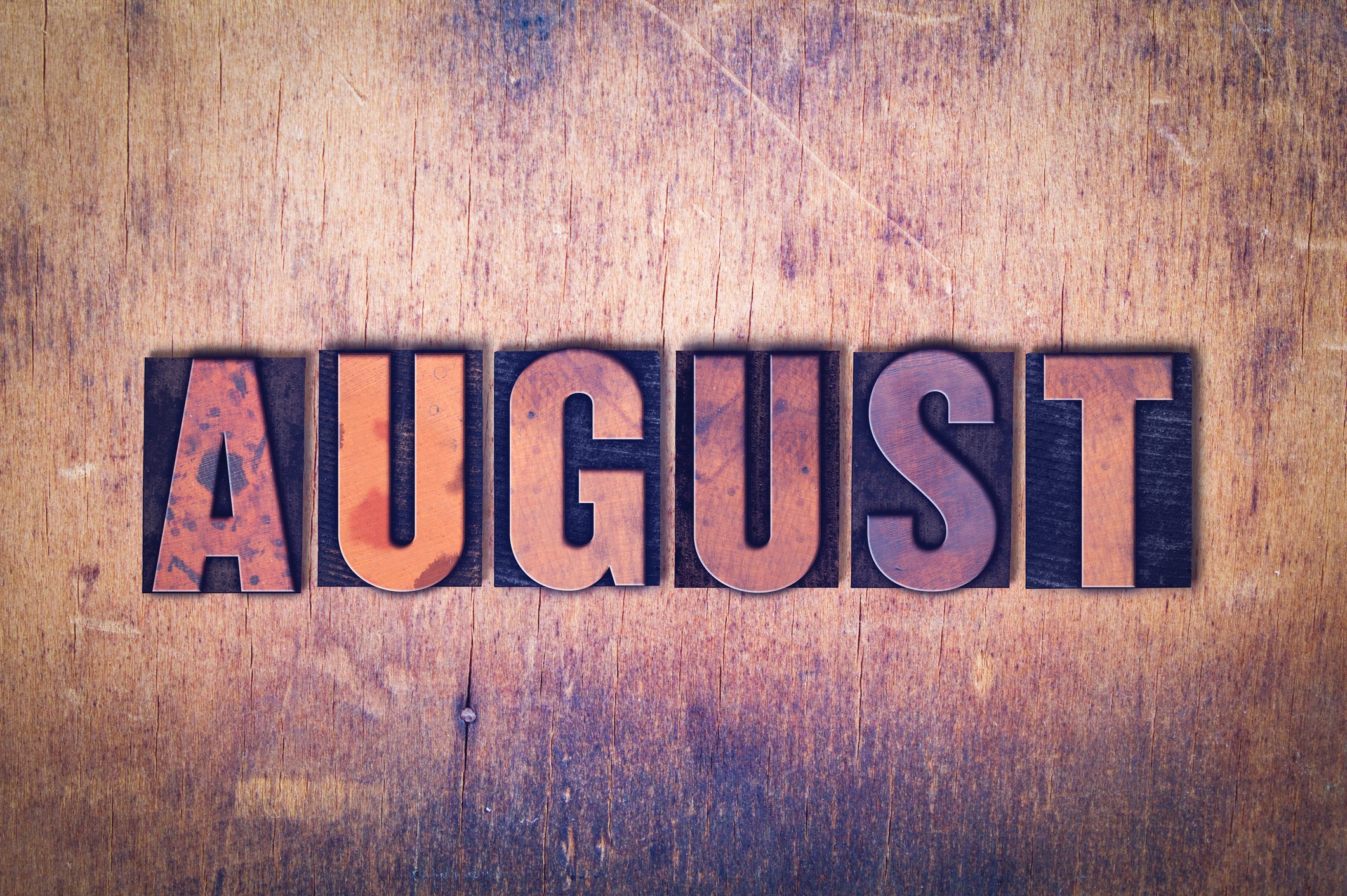 August spelled out in block letters on a wooden background.