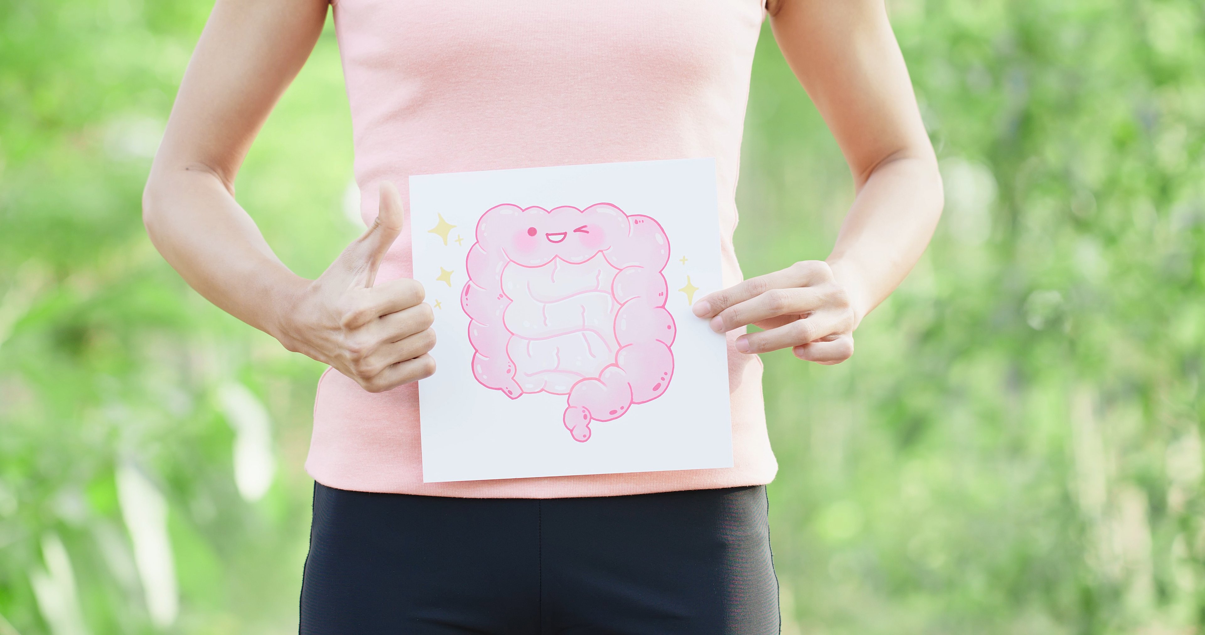 Woman holding a drawing of a smiling colon while giving a thumbs up.