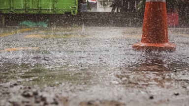 Rain falling near a an orange cone.
