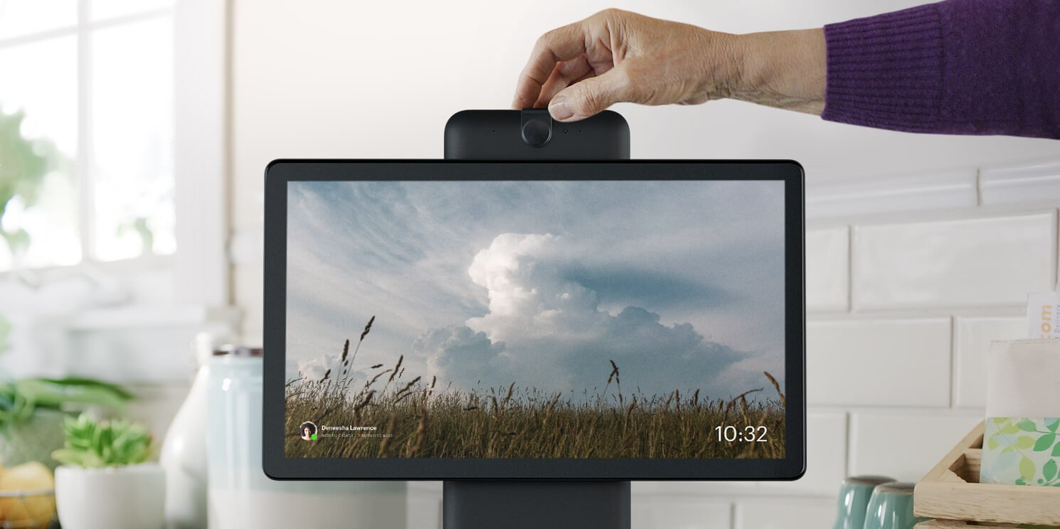A person's hand positioning the camera atop a Facebook Portal device.