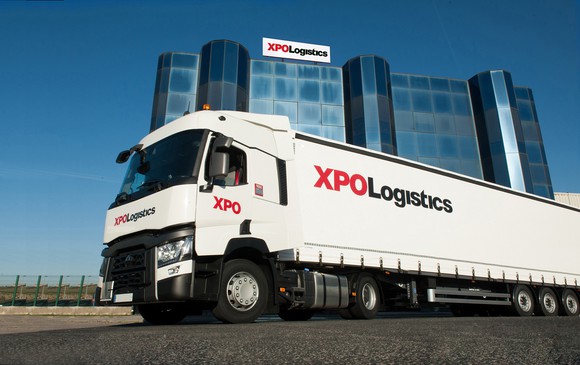 Truck in front of tall office building, both with XPO Logistics logos on them.
