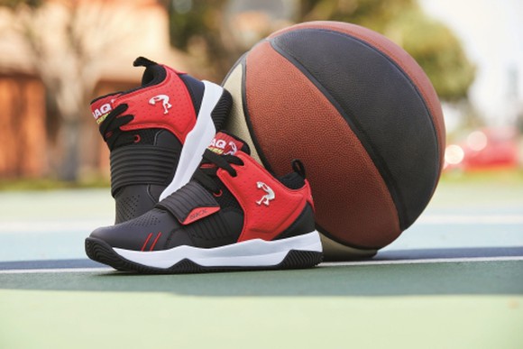 A pair of red, black, and white Shaq by Skechers basketball shoes sitting on a court with a basketball.
