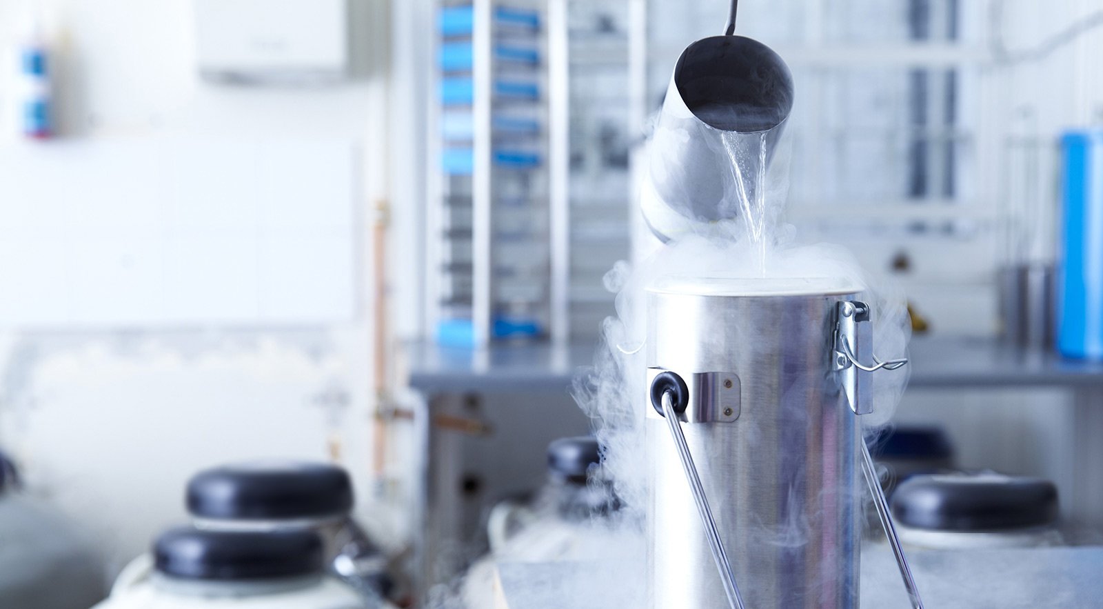 A lab setting with a cryogenic liquid being poured into a container.