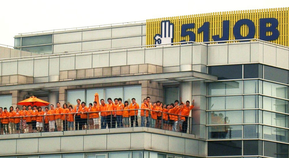 51job employees in orange shirts, on the patio outside of 51job headquarters in China.