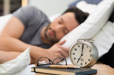 man sleeping with an alarm clock