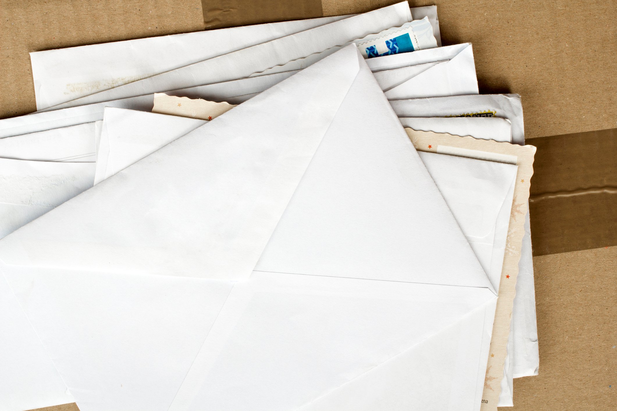 Various envelopes stacked on top of a cardboard shipping box.
