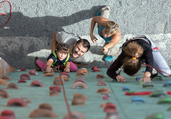 A family moving up a climbing wall.
