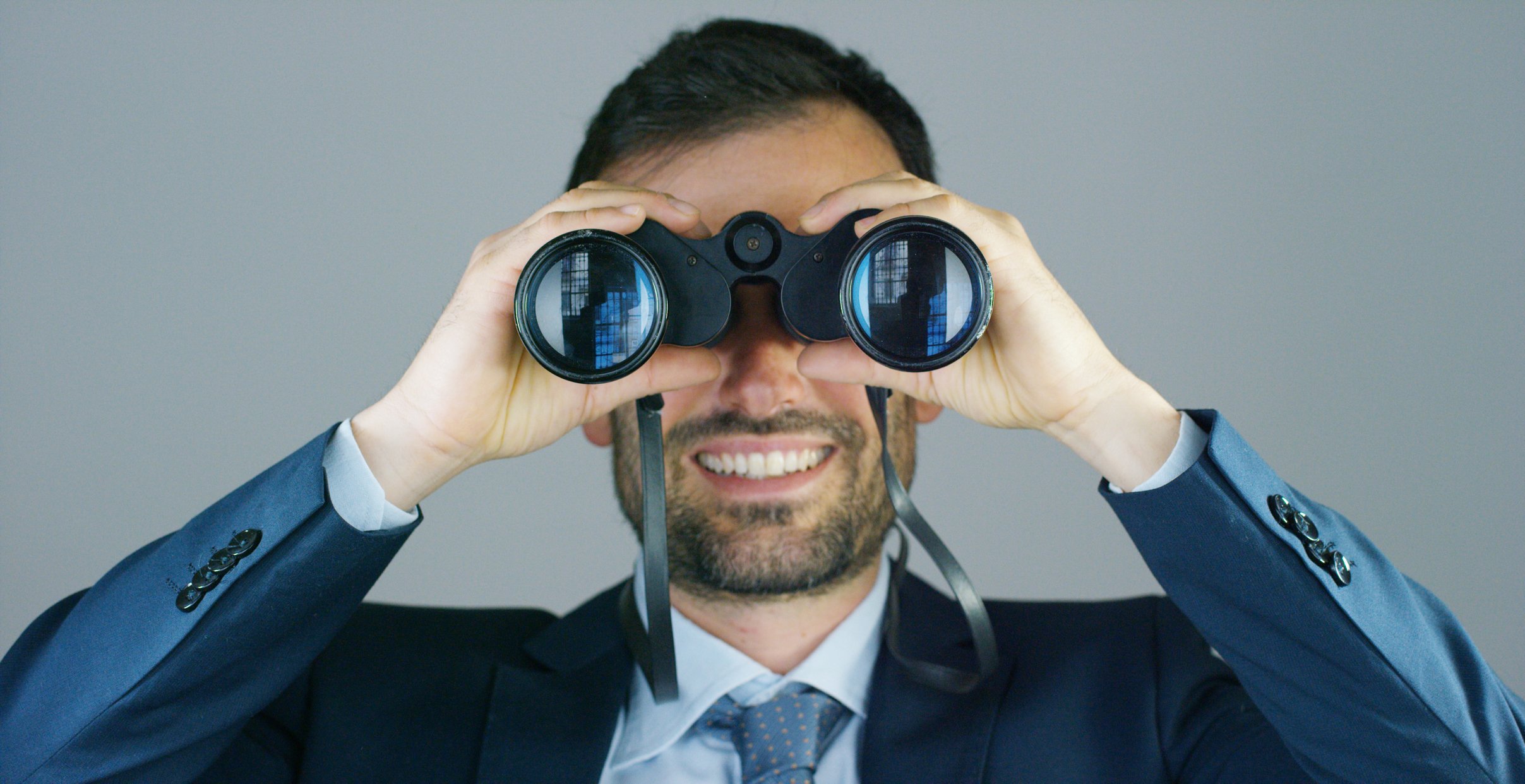 A businessman looks through a pair of binoculars.
