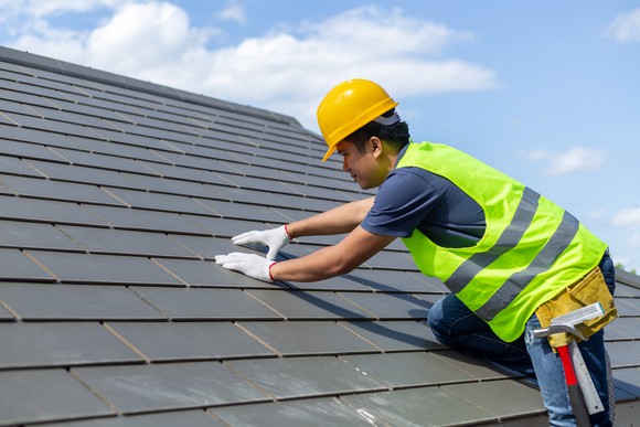 Worker installing shingles on a roof. 