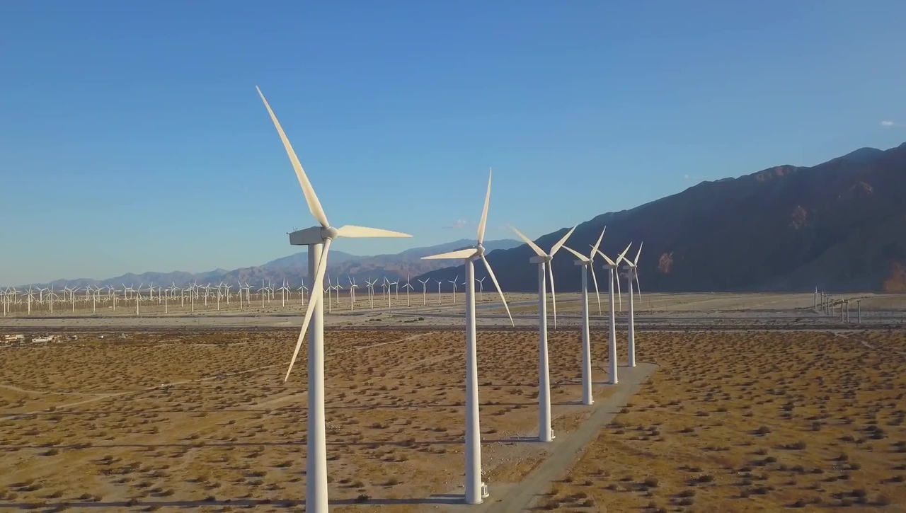 Row of a couple dozen wind turbines in a desert.