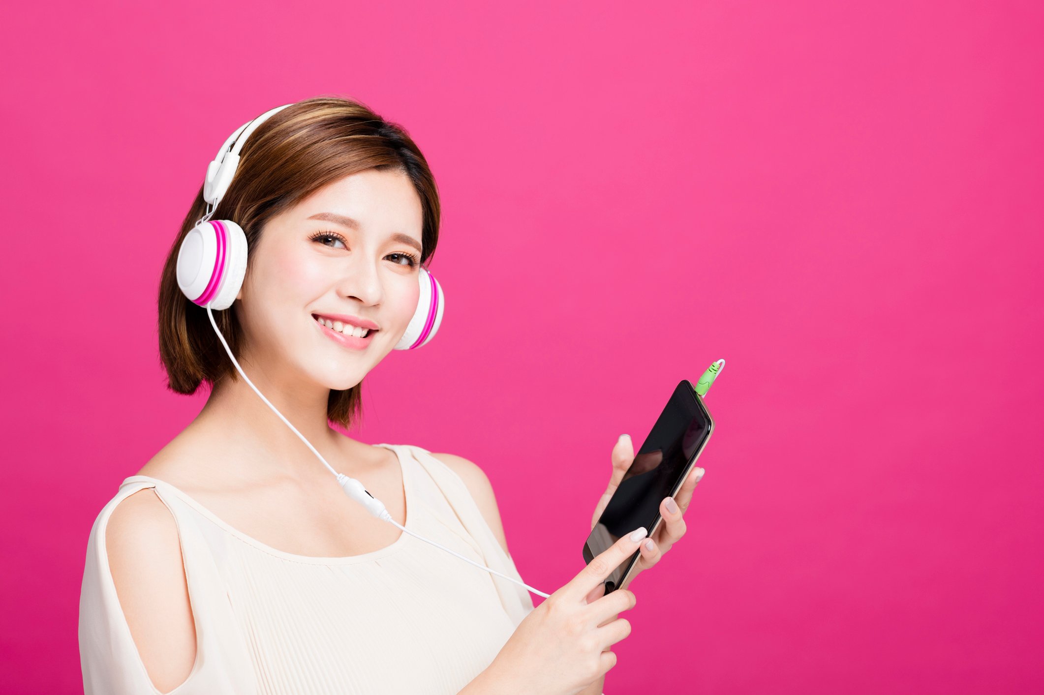 A young woman listens to music on her smartphone.