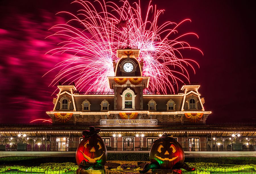 Fireworks behind the Main Street railroad station with a pair of Halloween jack-o-lanterns in front.