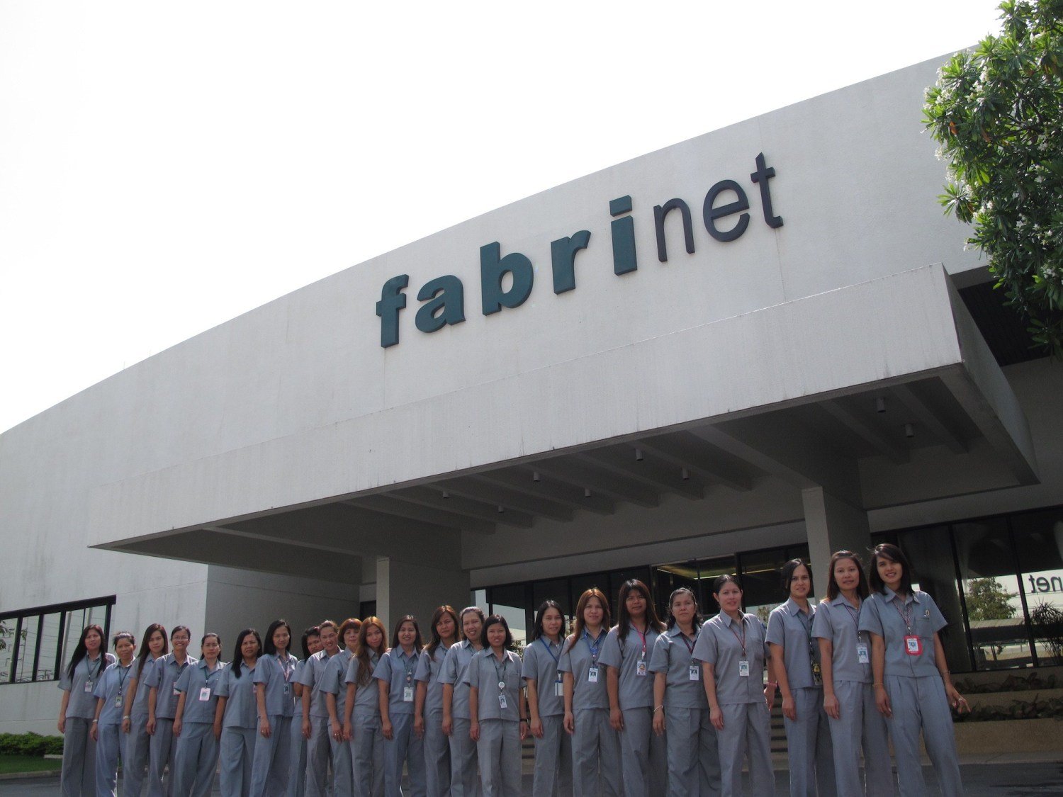 People standing in front of a Fabrinet facility.