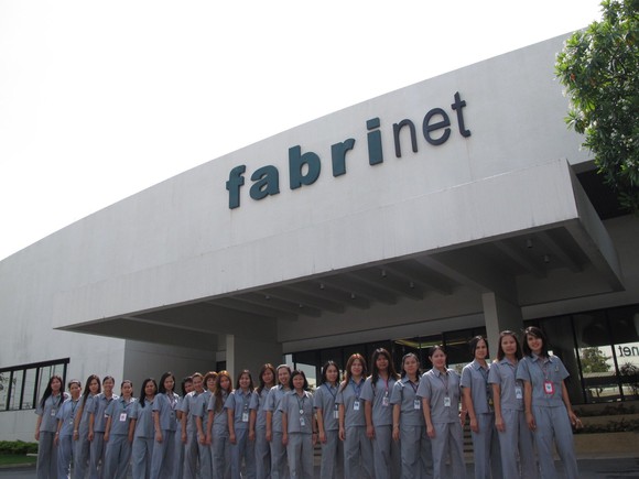 People standing in front of a Fabrinet facility.