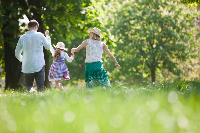 Parents lifting a child while walking in the park