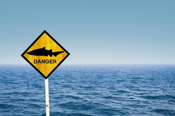 Open water with a sign that has a picture of a shark and danger written on it.