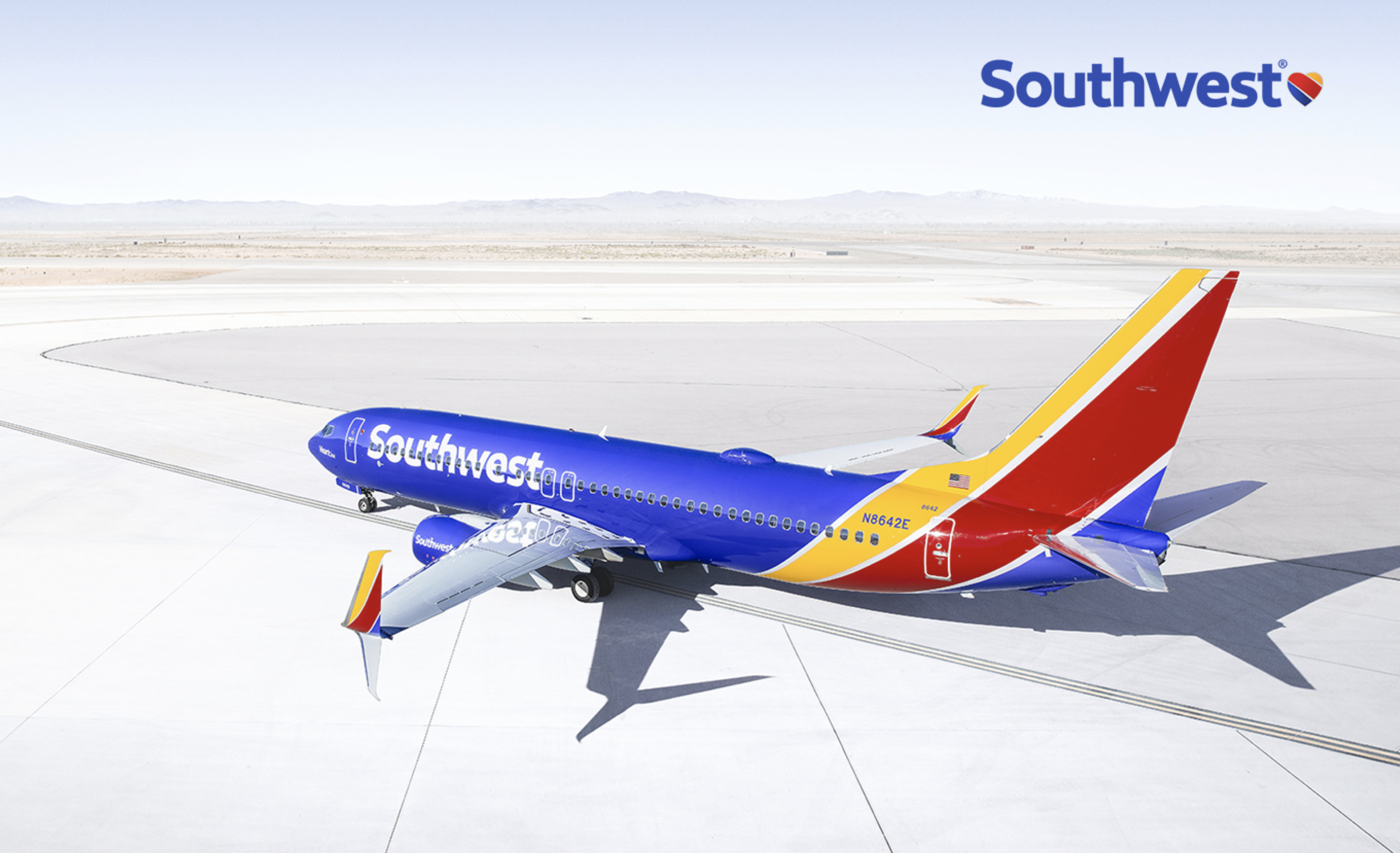 An aircraft painted blue, yellow, and red, sitting on a runway, with the Southwest corporate logo on the side.