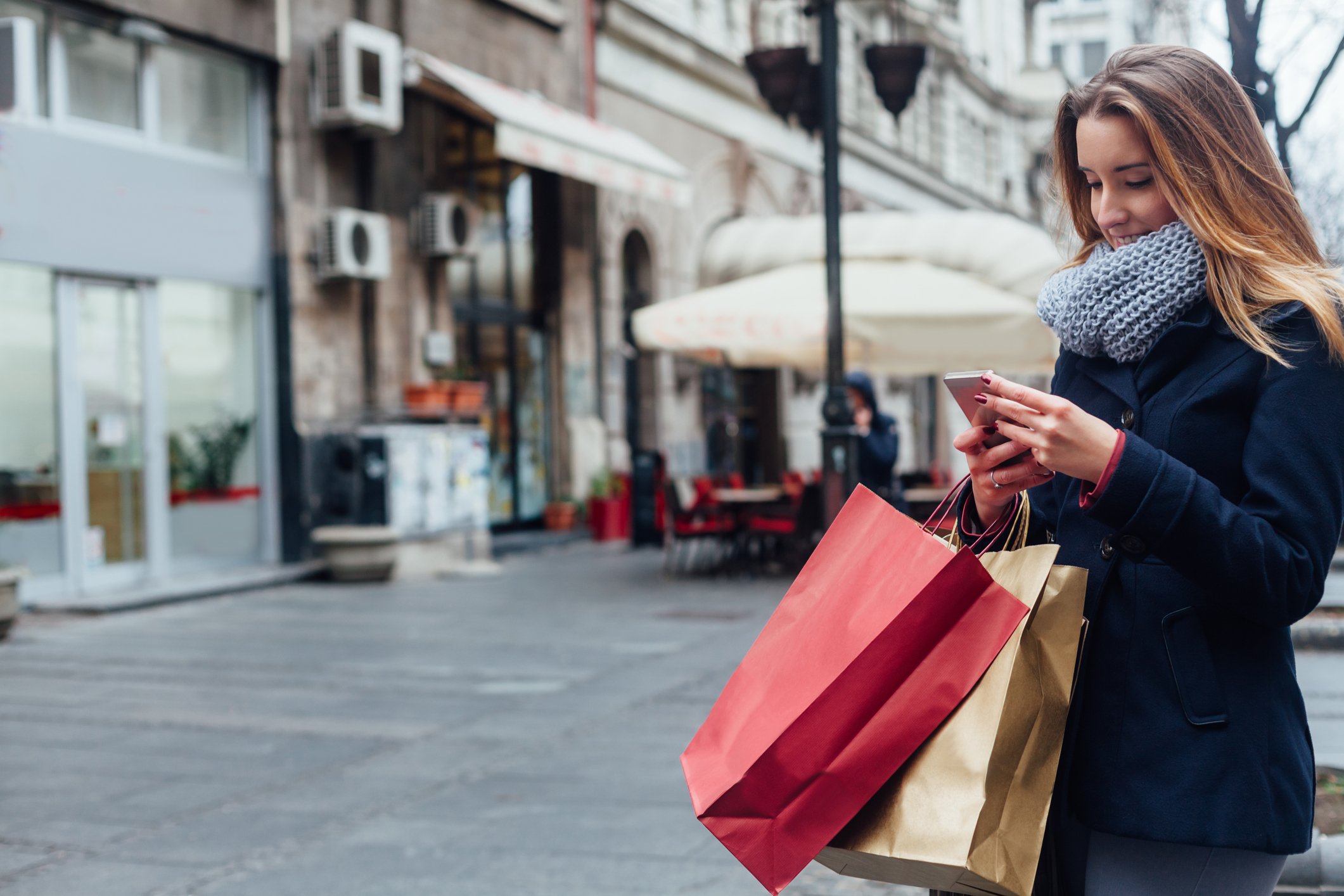 A woman dressed in a winter coat and carrying shopping bags.