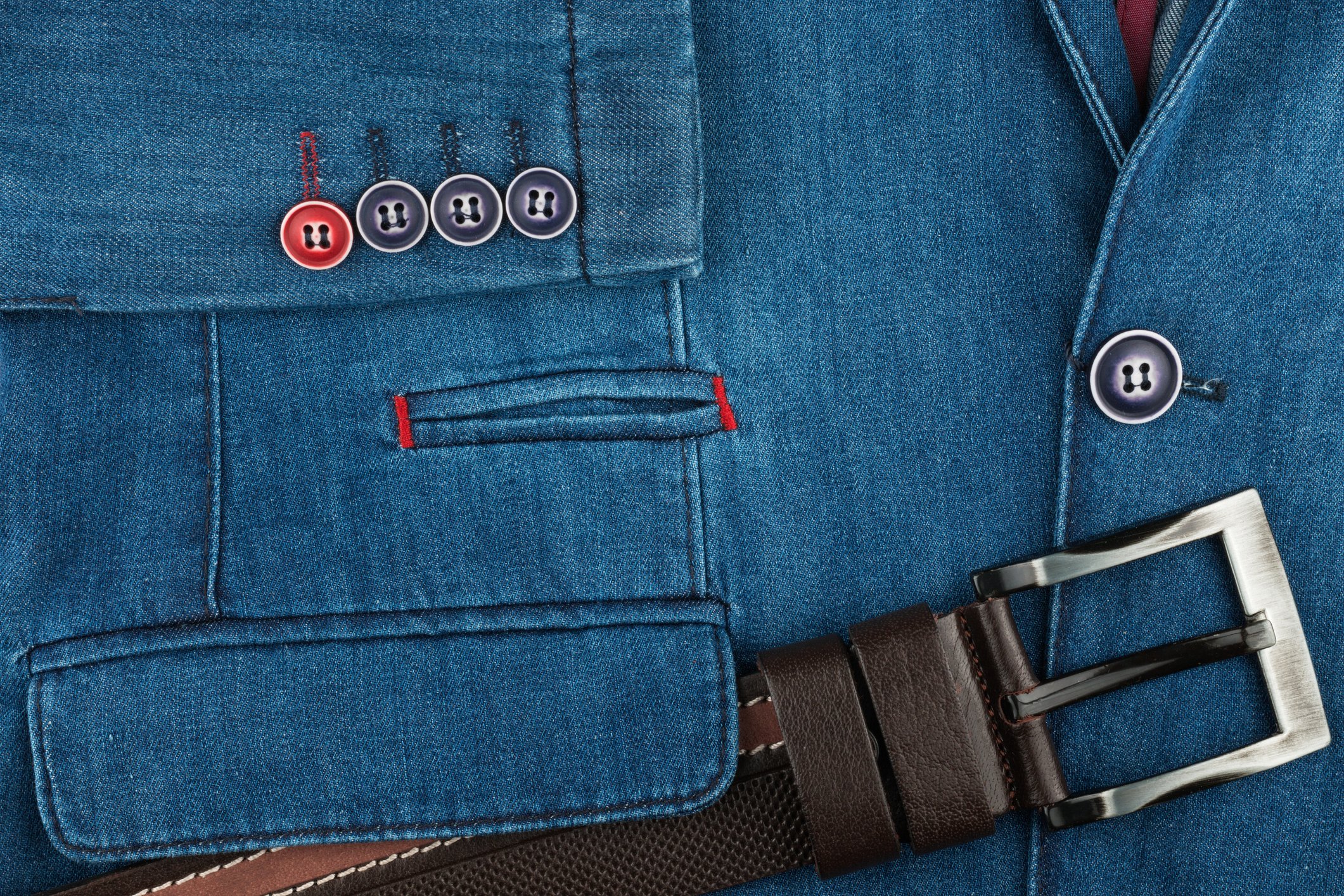 A leather belt rests on a denim jacket.