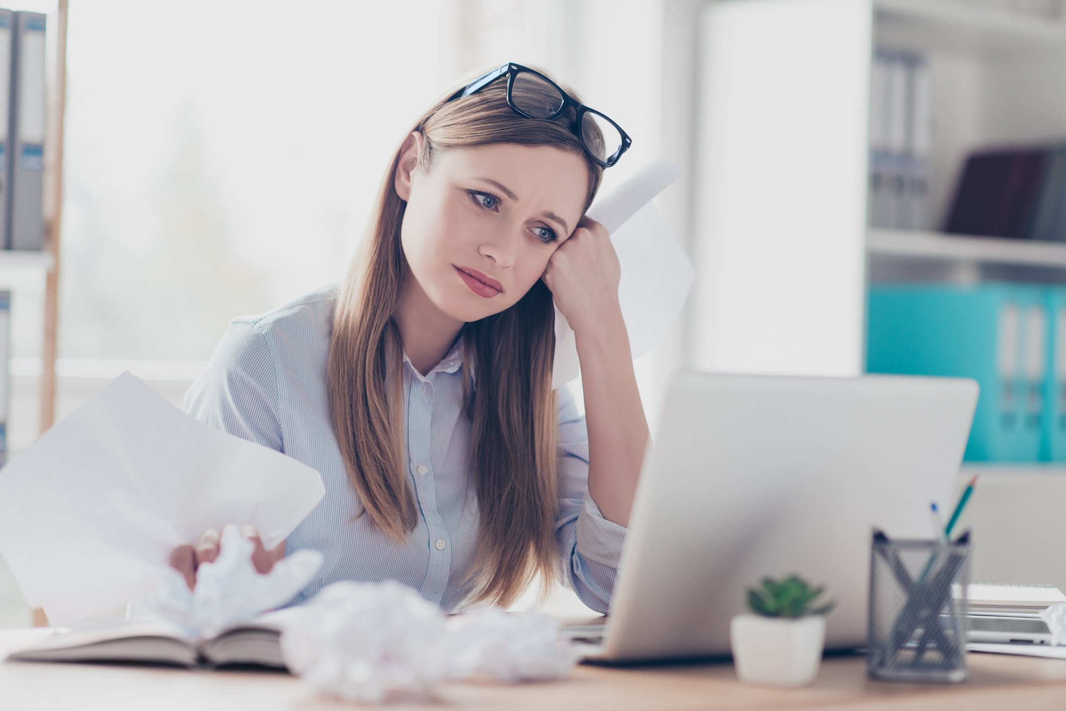 Woman sitting at laptop, resting her face on her hand 