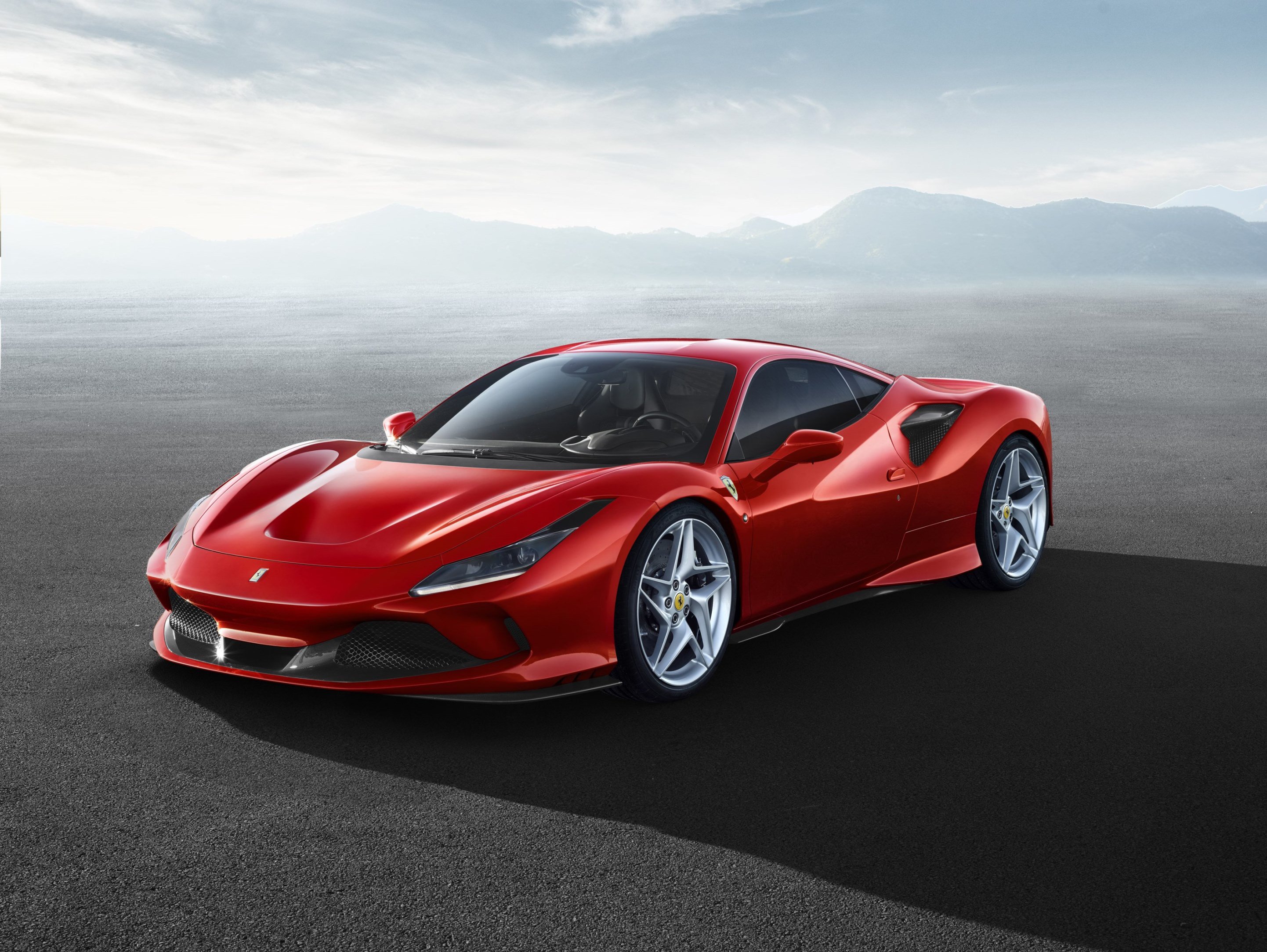 A red Ferrari F8 Tributo, with mountains in the background