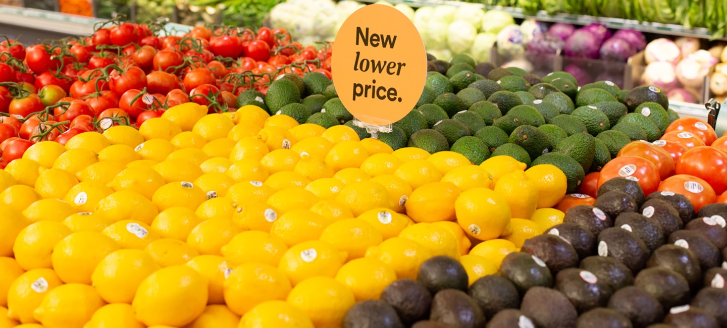 A produce stand with a sign that says new lower price.