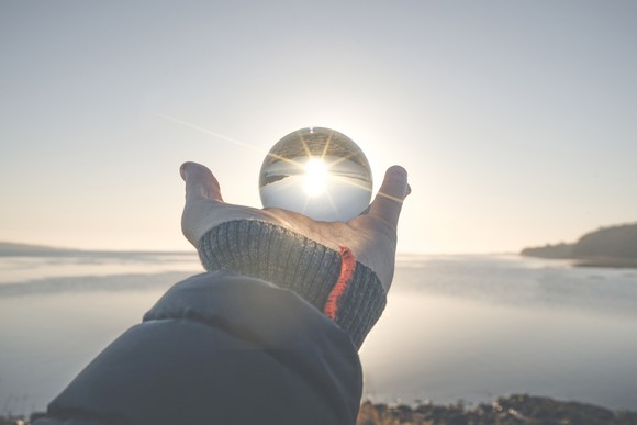 A hand holding a crystal ball toward the horizon