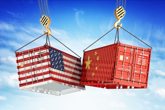 Two shipping containers, one painted with American flag and the other with Chinese flag.