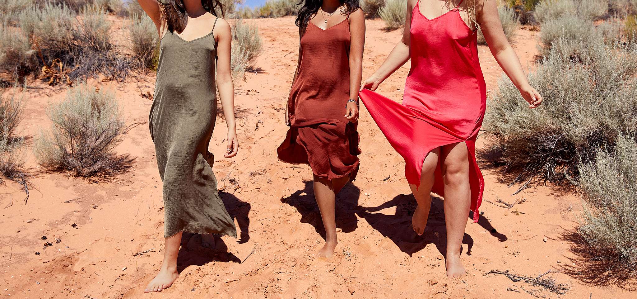 An Aerie ad: Three women wearing slip dresses and walking on sand.