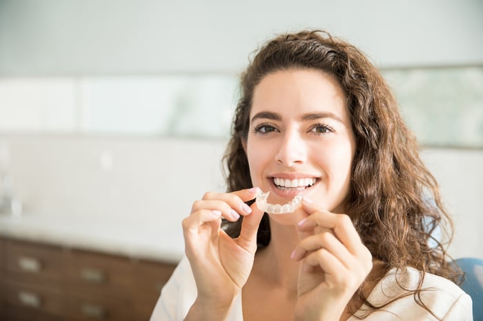 Smiling woman displays her orthodontic device.