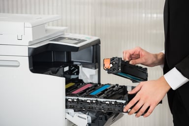 Businesswoman changing ink cartridge in a printer