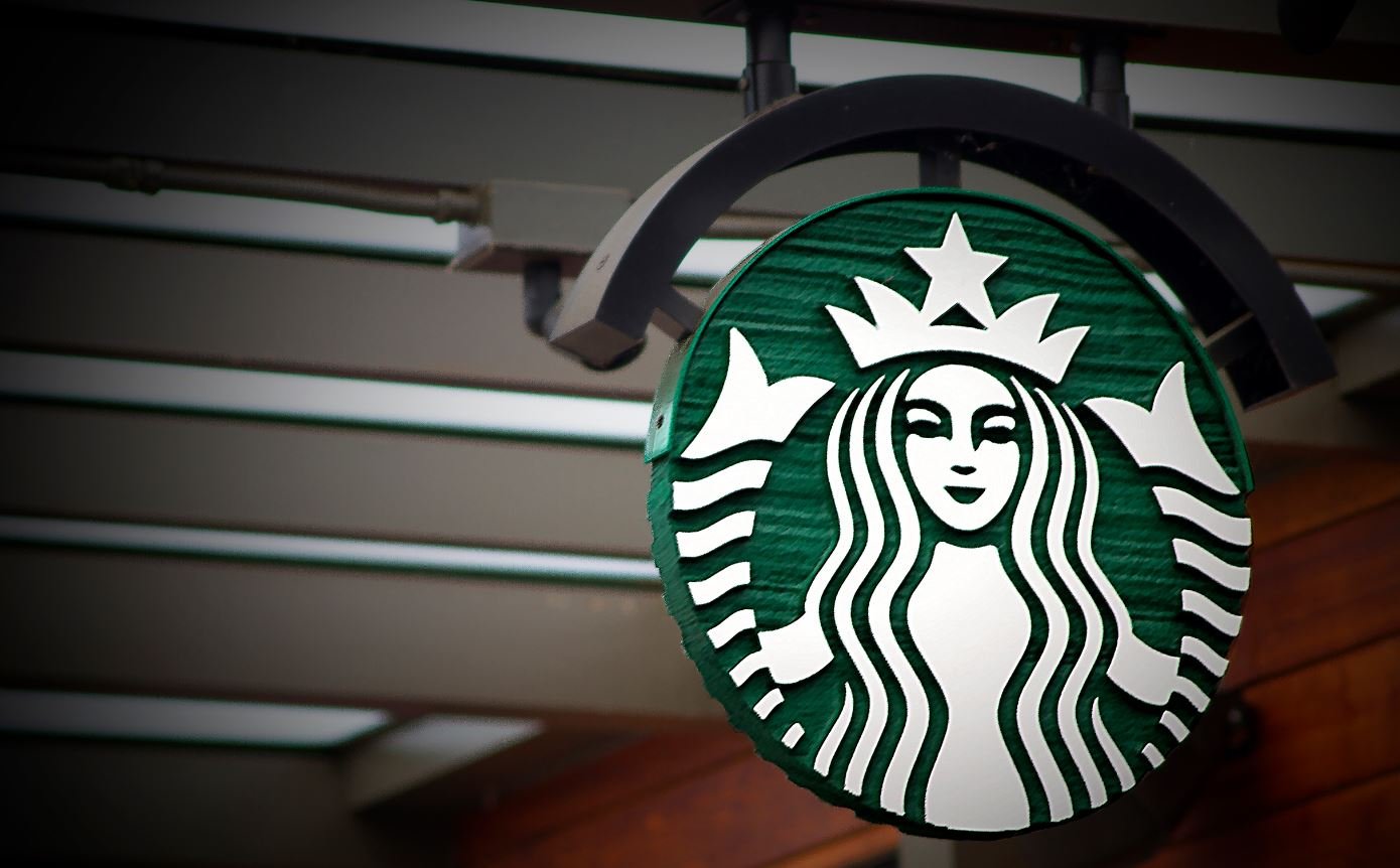 Starbucks mermaid logo on circular sign hanging from ceiling.