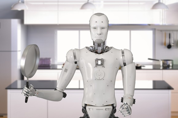 Robot holding frying pan in kitchen