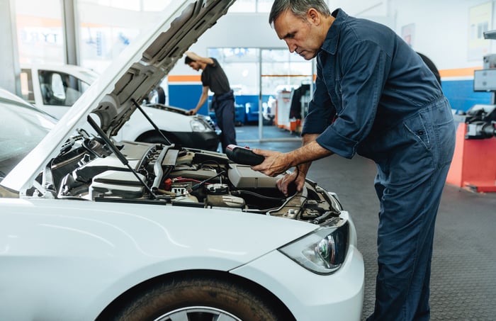 A man works on a car with its hood open.