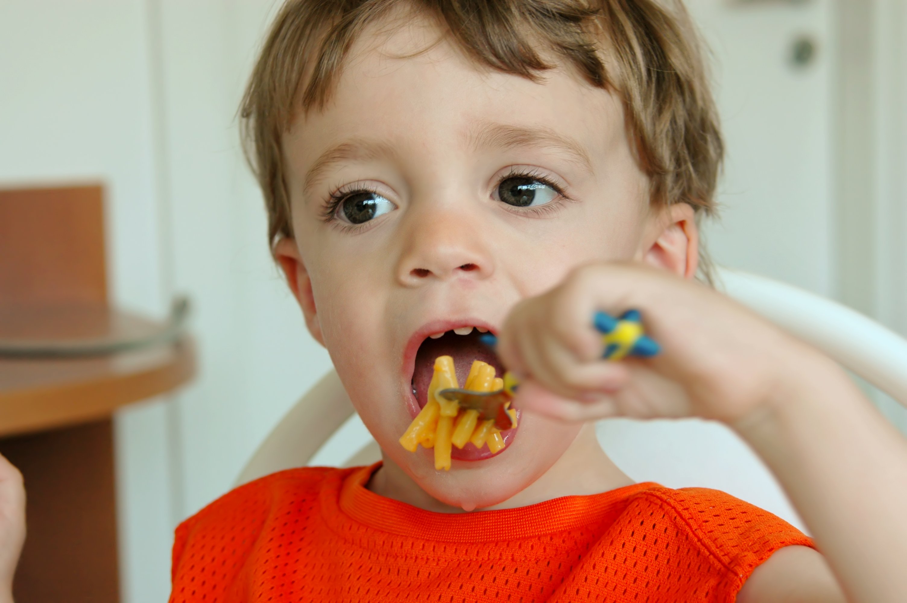 A little boy eating mac and cheese.