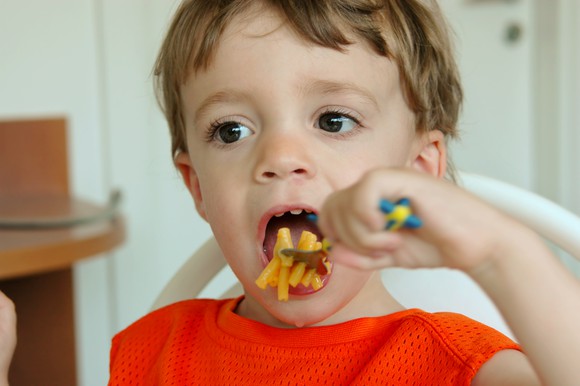 A little boy eating mac and cheese.