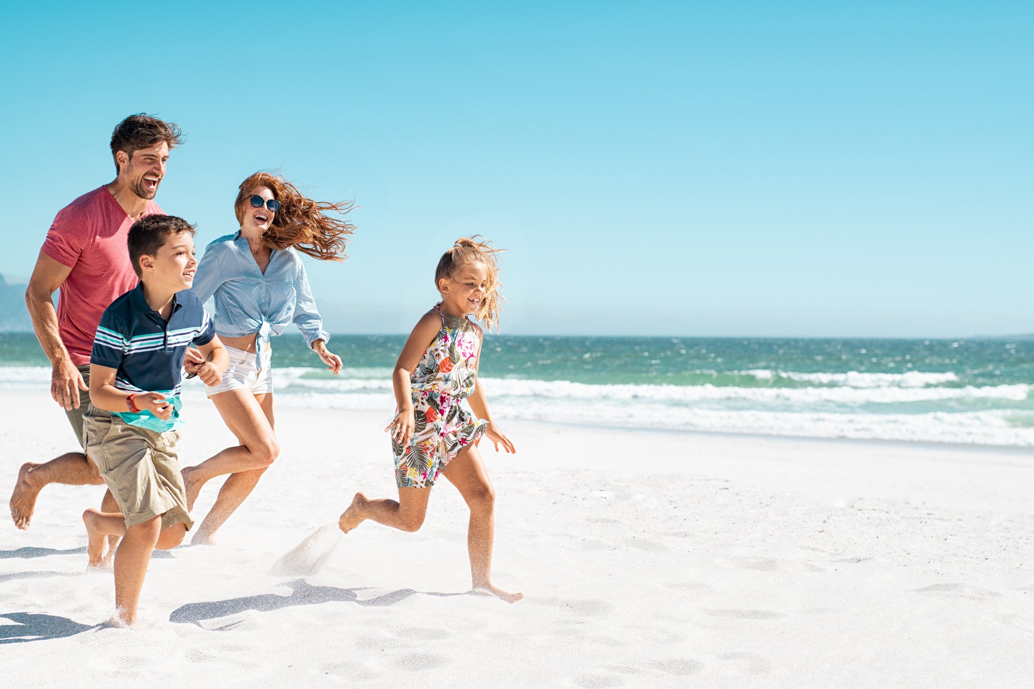 A family with kids is running on a beach.