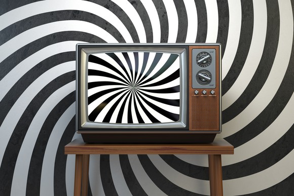 A TV showing a sprial pattern in front of a backdrop showing the same spiral pattern.