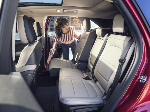 A woman moving the backseat of a red 2020 Ford Escape.