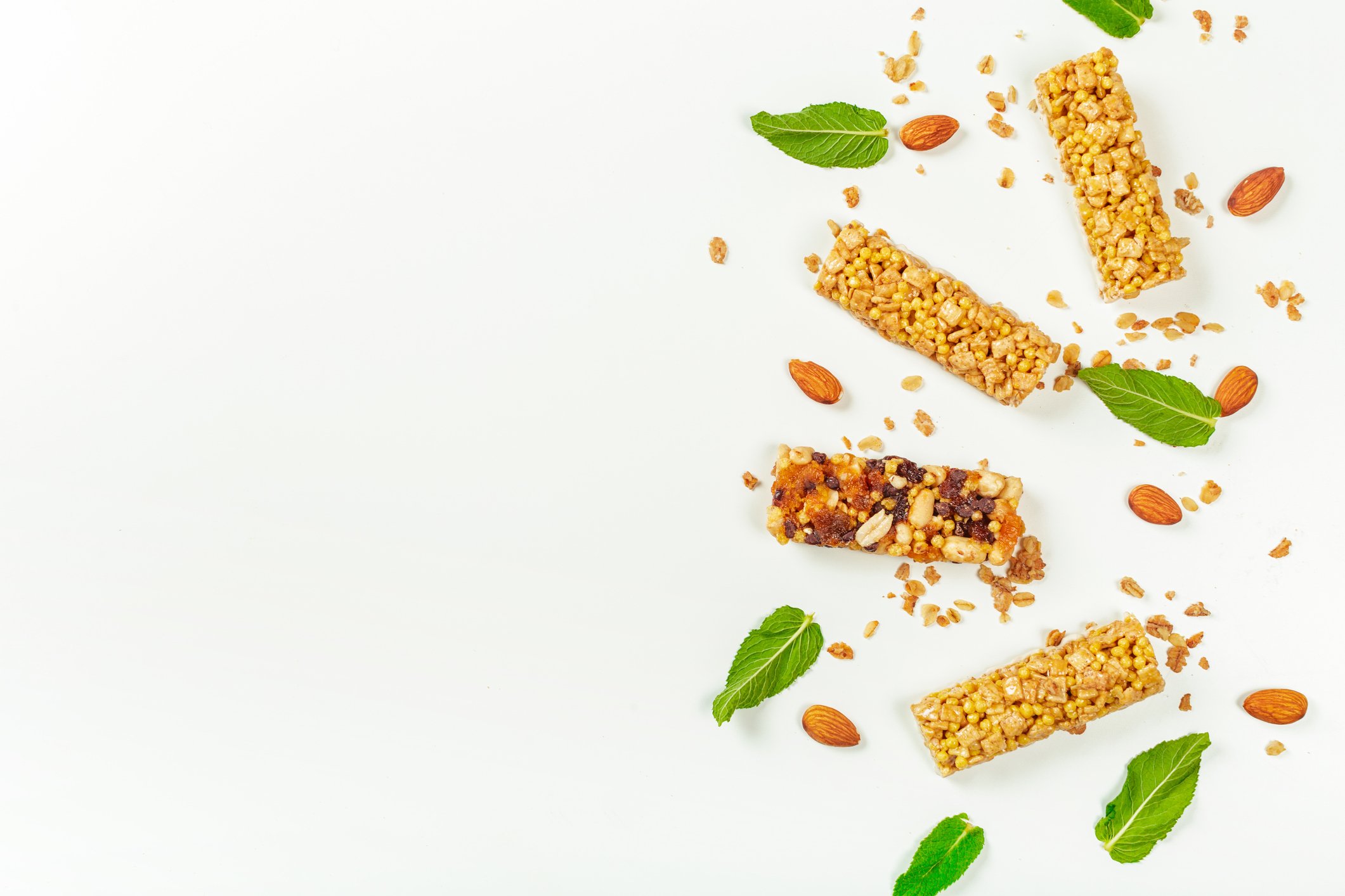 Granola bars and basil leaves on a white background.