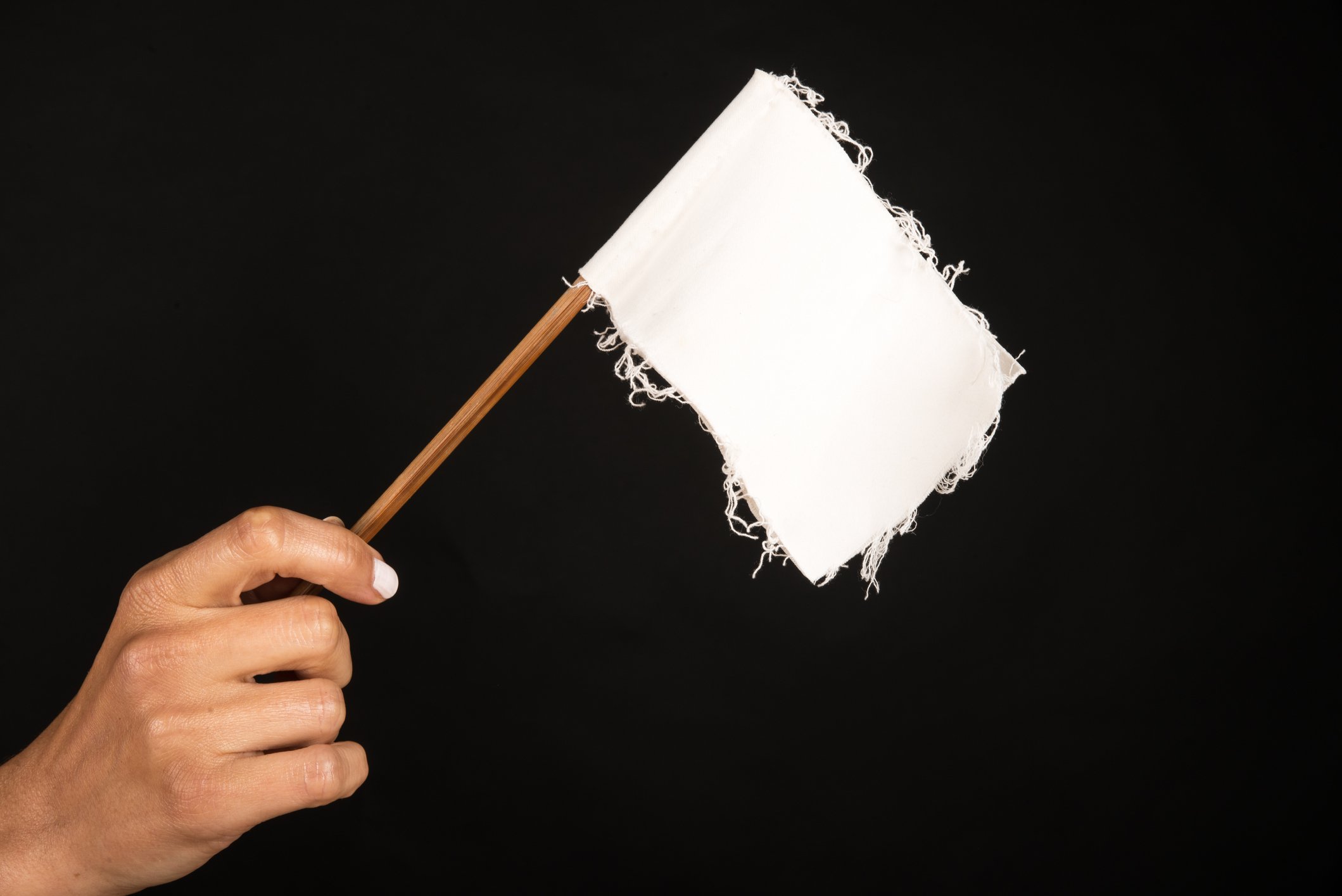 Hand holding a frayed white flag.