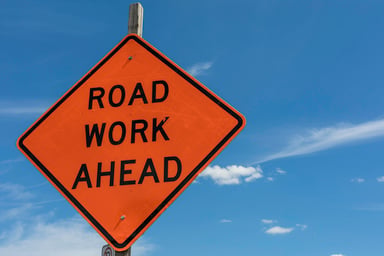 Orange sign reads Road Work Ahead