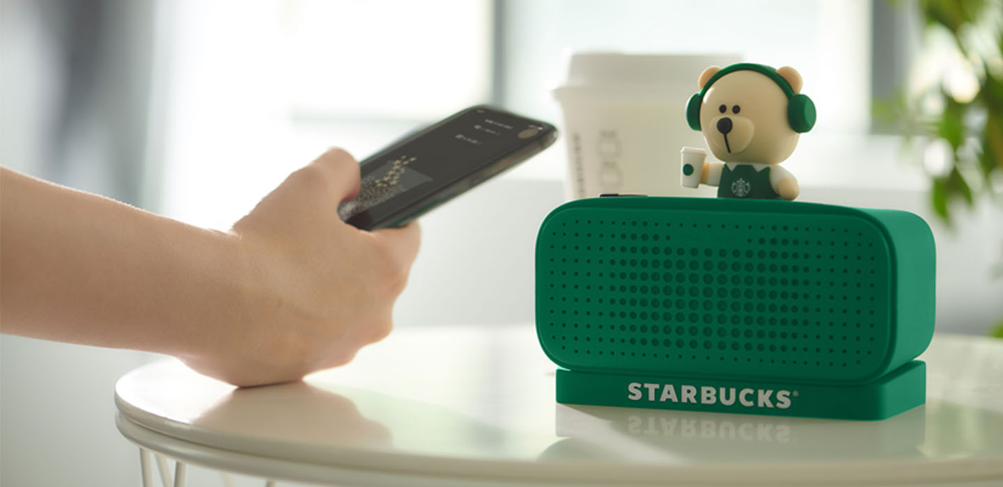 A speaker says Starbucks while a person holds a remote control.
