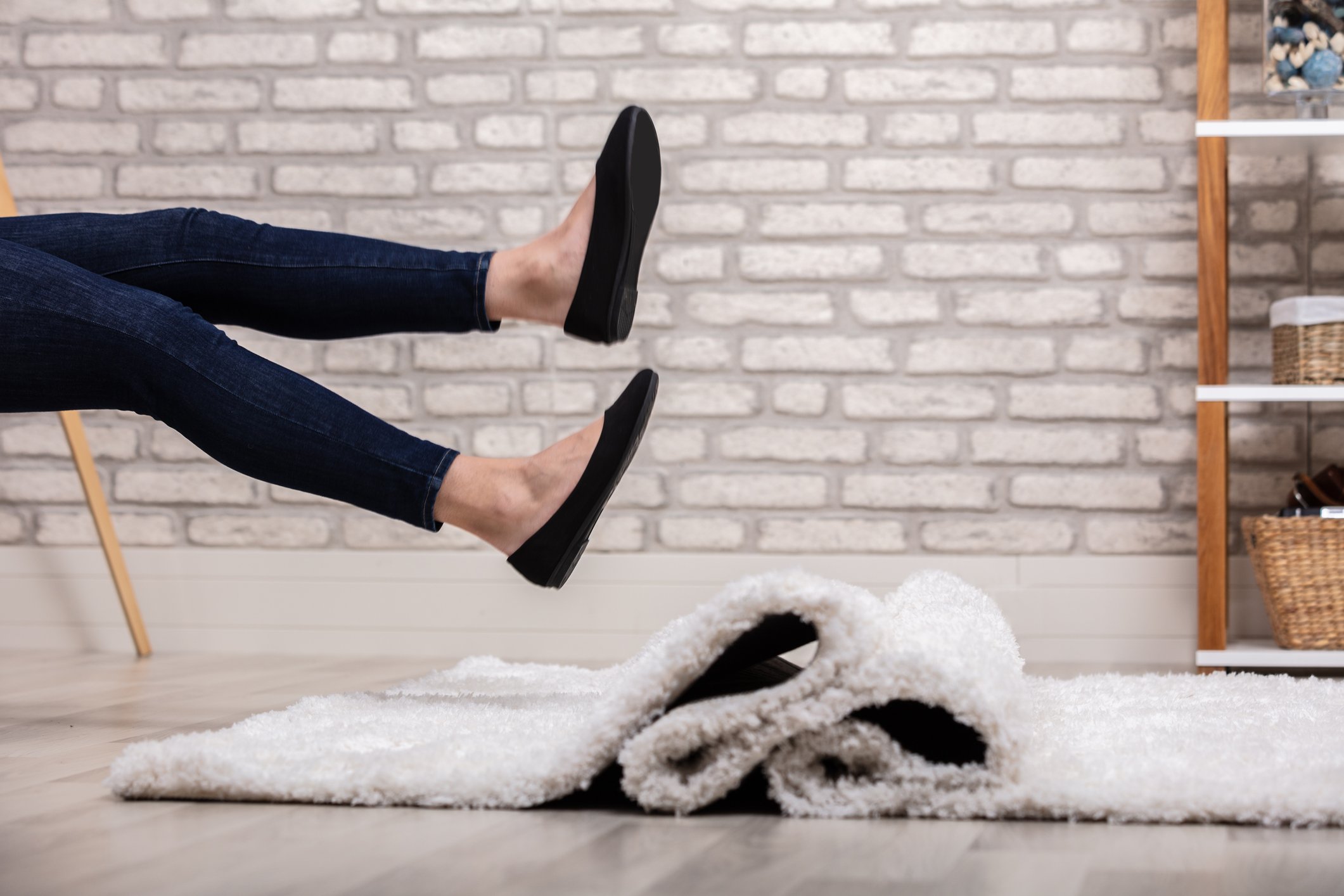 Woman falling because a carpet runner has slipped out from under her feet.