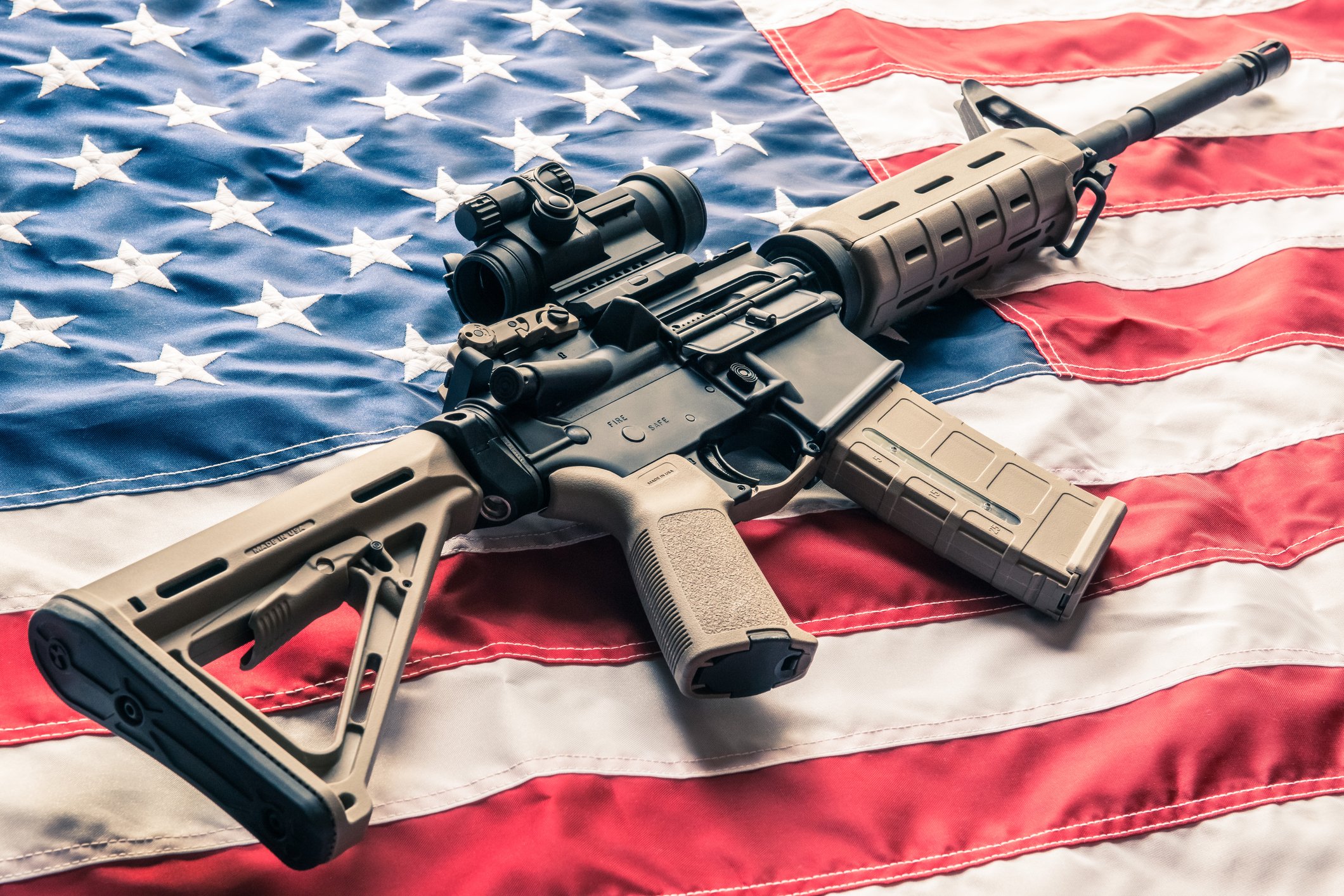 An AR-style rifle on top of an American flag