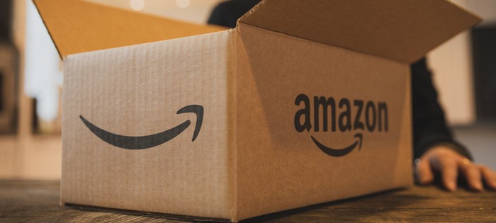 An open Amazon box with part of a person's hand visible next to it.